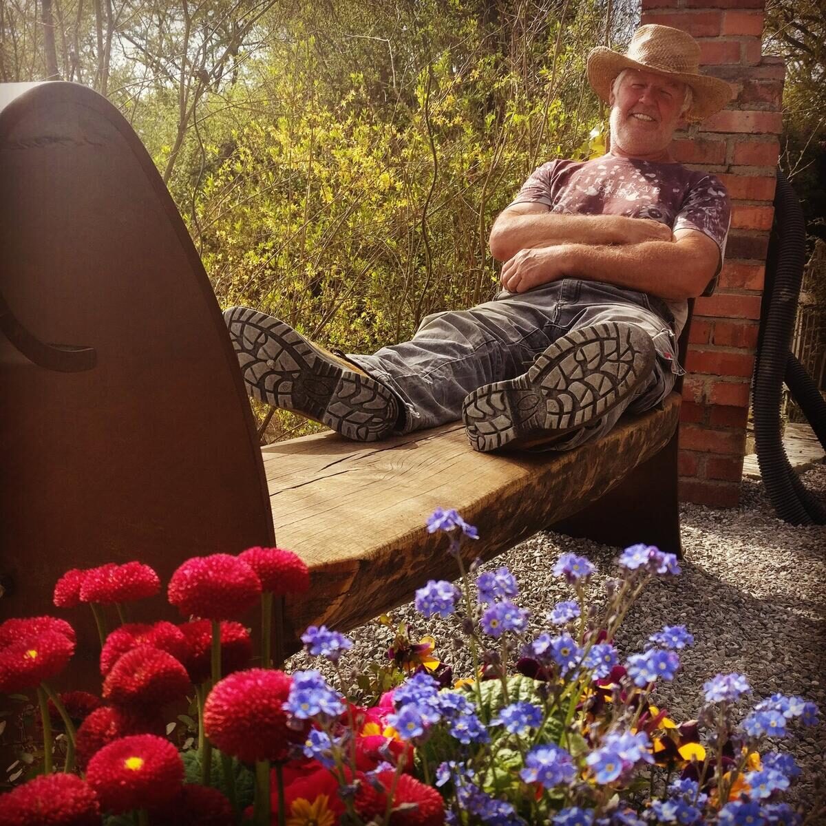 Klaus entspannt auf einer Bank im blühenden Garten